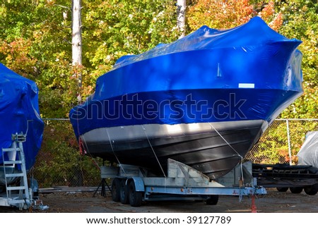 shrink wrapped power boat in autumn woods