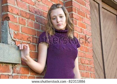teenage girl standing by old brick wall