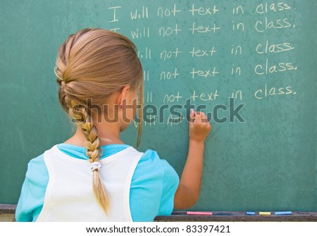 young girl writing lines on green chalkboard.