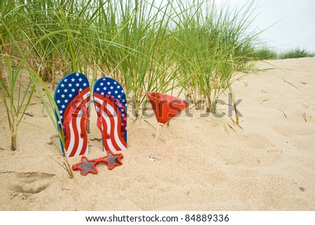 patriotic flip-flops with cocktail glass in sand
