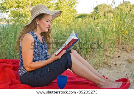 woman reading a book on a red blanket