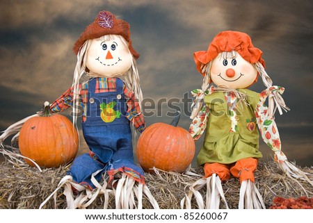 scarecrow couple with pumpkins on hay bales