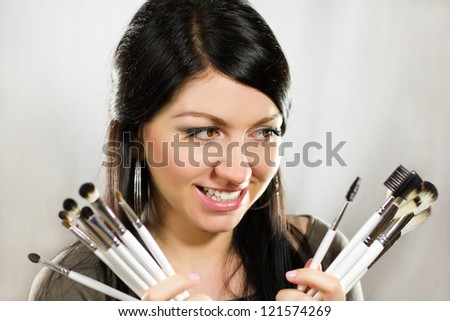 Beautiful woman holding makeup brushes set and looking on it