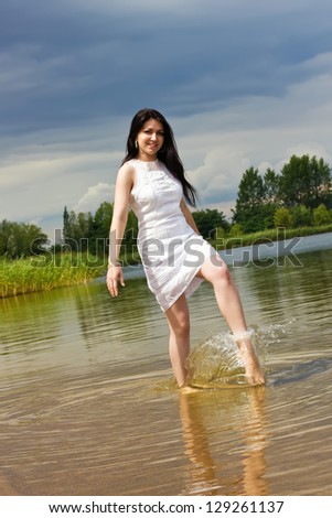 Young woman makes fun on the lake doing splashes of water