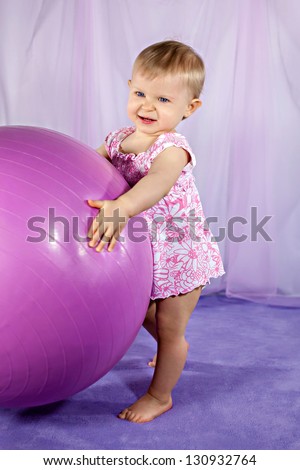 Little girl playing with a big gymnastic ball
