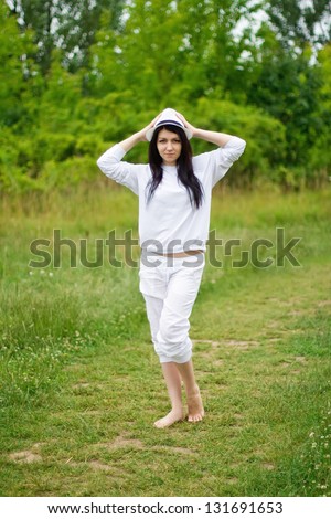 A young girl standing in the green grass area