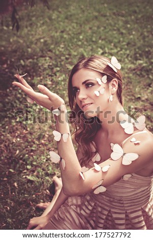 Beautiful young female with many butterflies on her face and hands