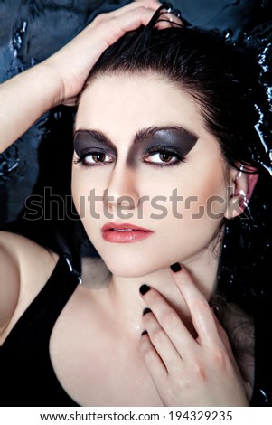 Close-up woman face with smoky eyes lying in water