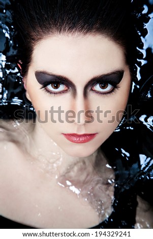 Close-up woman face with smoky eyes lying in water