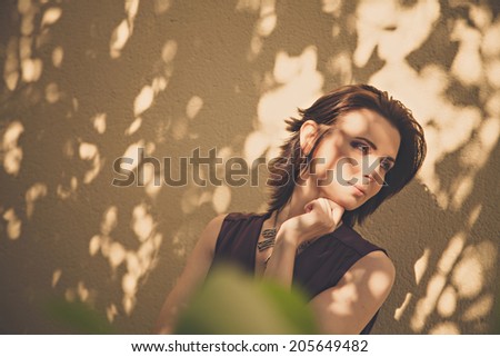 Pretty woman standing in shadow of tree