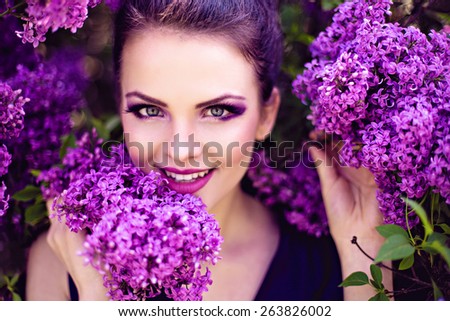 Beautiful girl in lilac ball dress among the flowers in the garden