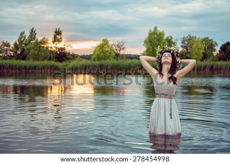 Young beautiful drowned woman in grey dress staying in the water at the lake