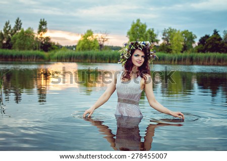 Young beautiful drowned woman in grey dress in the water