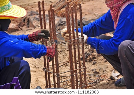 builder workers knitting metal rods bars into framework reinforcement for concrete pouring at construction site.