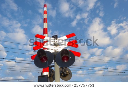 Flasher near a rail crossing under a clouds blue sky