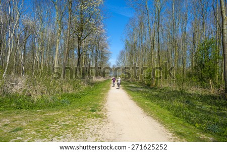 Two cyclists on a dirt road in a forest in spring