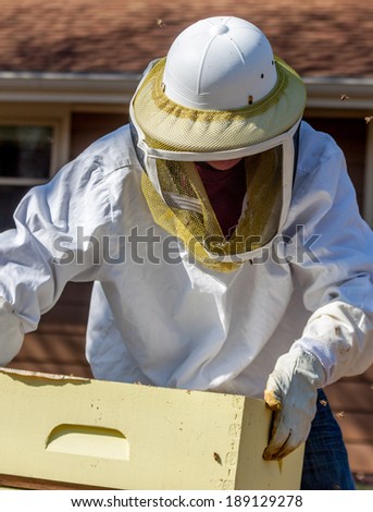 A beekeeper moves the boxes around after inspecting the hive