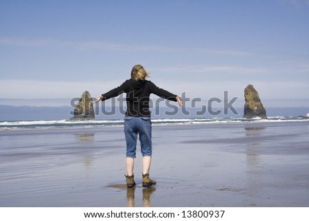 A woman on the beach with arms out stretched enjoying the sun