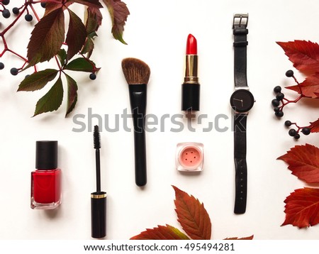 Decorative flat lay composition with cosmetics, woman accessories, decorated with autumn leaves and berries. Flat lay, top view on white background, fashion still-life
