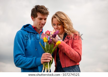 Couple Dutch tourists are plucking colorful bouquet tulips in the flower fields