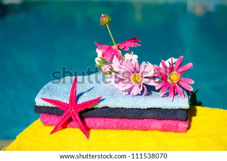 Silk flowers and towels near swimming pool