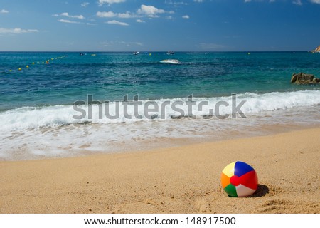 Inflatable beach ball in the sand near the water line at the Spanish beach