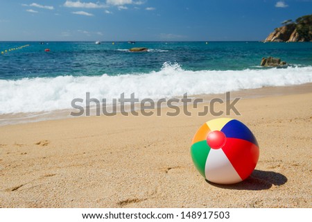 Inflatable beach ball in the sand near the water line at the Spanish beach