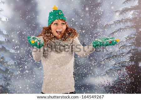 Portrait of woman in winter with snow and hat and gloves of Christmas tree in snowstorm