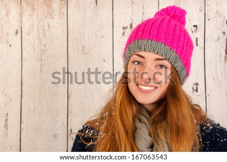 Portrait girl with pink winter hat in front of wooden background