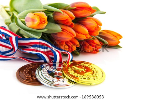 Dutch medals in gold, silver and bronze in front of orange tulips isolated over white background