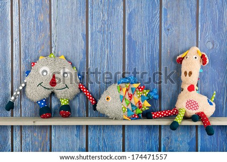 Stuffed colorful funny fish at home on blue wooden background