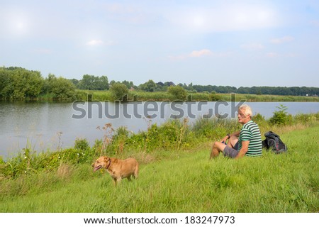Man with dog sitting in nature river landscape