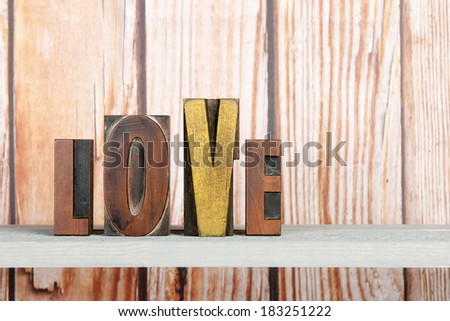 Love written with vintage used print letters on wooden background