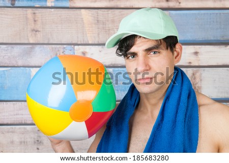 Portrait young handsome man in front of wooden blue vintage background with ball and cap