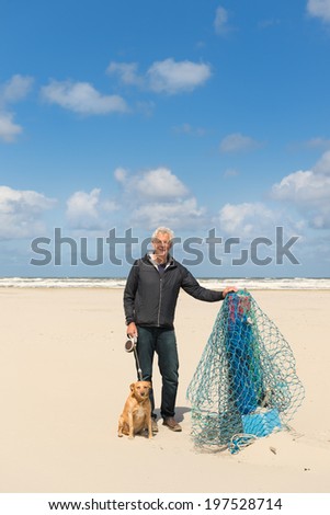 Man with dog near Wooden pole at the beach of Dutch wadden island Terschelling