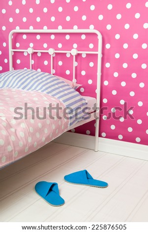 Bedroom with pink wallpaper and striped pillow