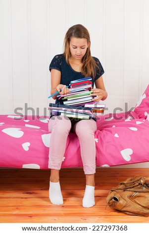 Fourteen year old girl with many schoolbooks and too many homework
