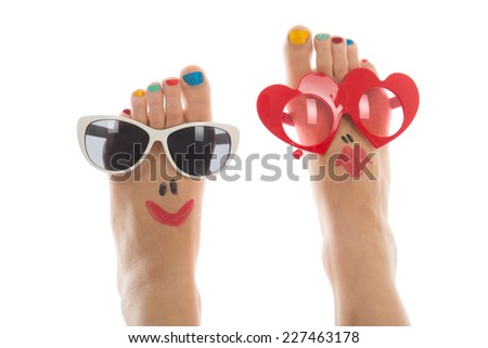 Happy and funny caucasian summer feet with colorful nail polish and sunglasses