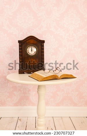 Vintage table in interior with old wall paper and clock