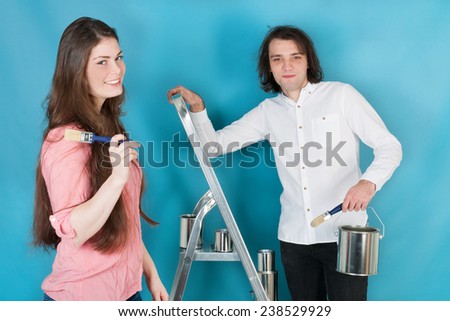 Young couple with paint and brushes in interior