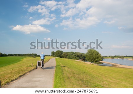 Landscape with river in Holland and man on bike with doggy car