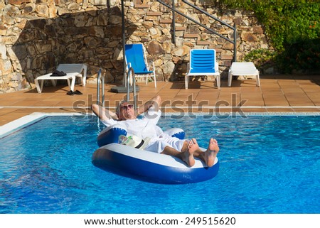 wealthy man relaxing in own swimming pool