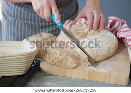 Senior woman cutting fresh baked rustic brown bread