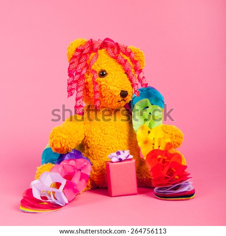 Stuffed birthday bear with present on pink background