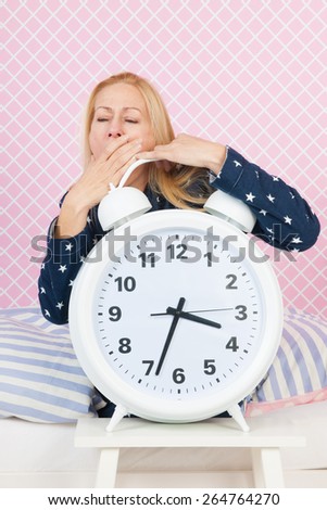 Blond woman of mature age with insomnia and big alarm clock