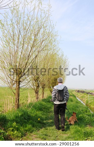 walking the dog with backpack in typical Dutch landscape