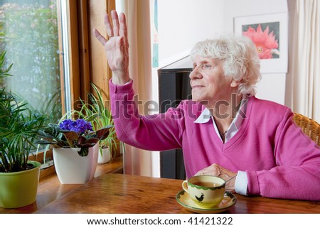 Elderly lonely woman saying goodbye to people outside