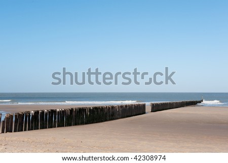 Beach in Holland with wave breaker from wooden poles