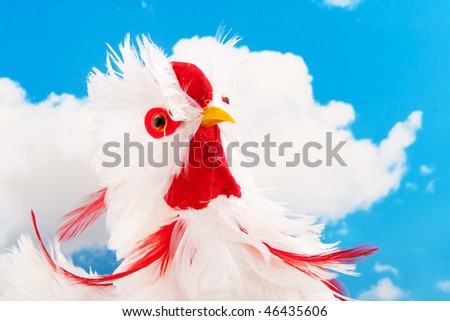Head of a white toy chicken in front of a blue sky