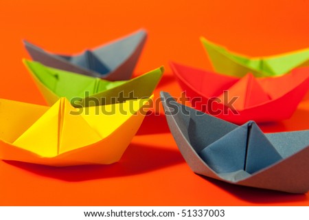 paper boats in many colors on orange background